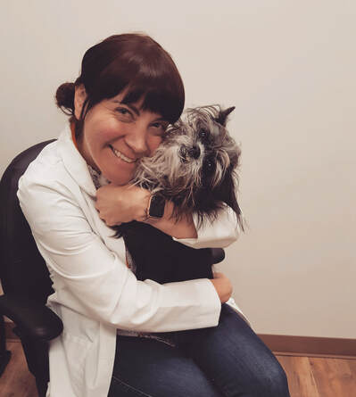 Dr. Jenny Bennett holding a small dog and smiling.